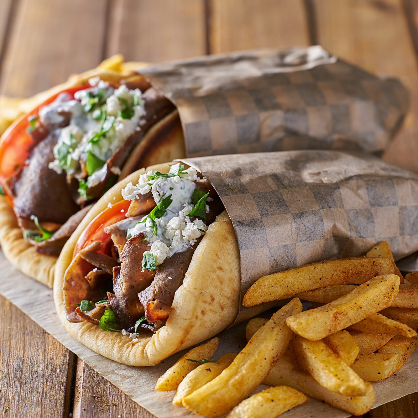 tasty greek gyros with fries with feta cheese and tzatziki sauce wrapped in paper